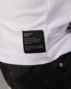 Close-up of a white shirt with a black rectangular brand label reading Southbound. Objective, worn with dark jeans.