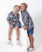 Two children wearing the Kids Safari animal print jerseys in zebra print