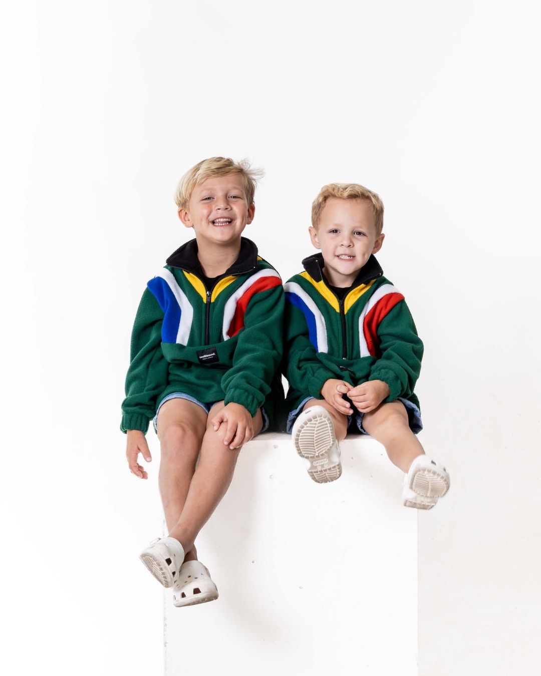 Two children wearing the Kids polar fleece SA flag jerseys in the colour green
