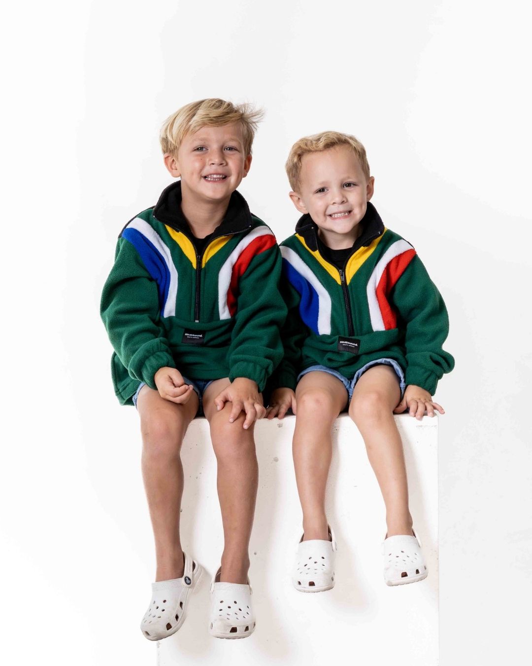 Two children wearing a Kids polar fleece SA flag jersey in the colour green