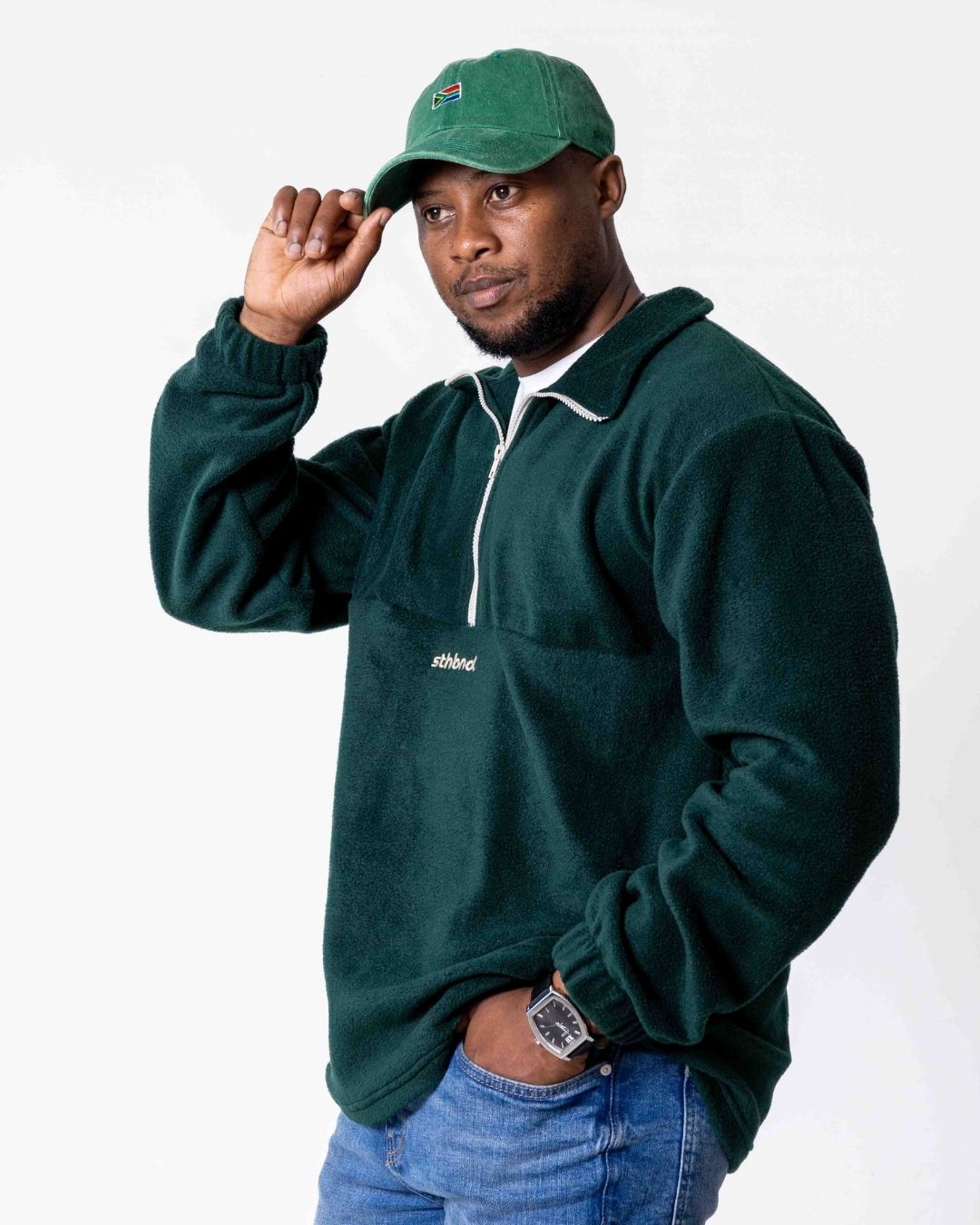 Man wearing a green pullover and cap on a white background