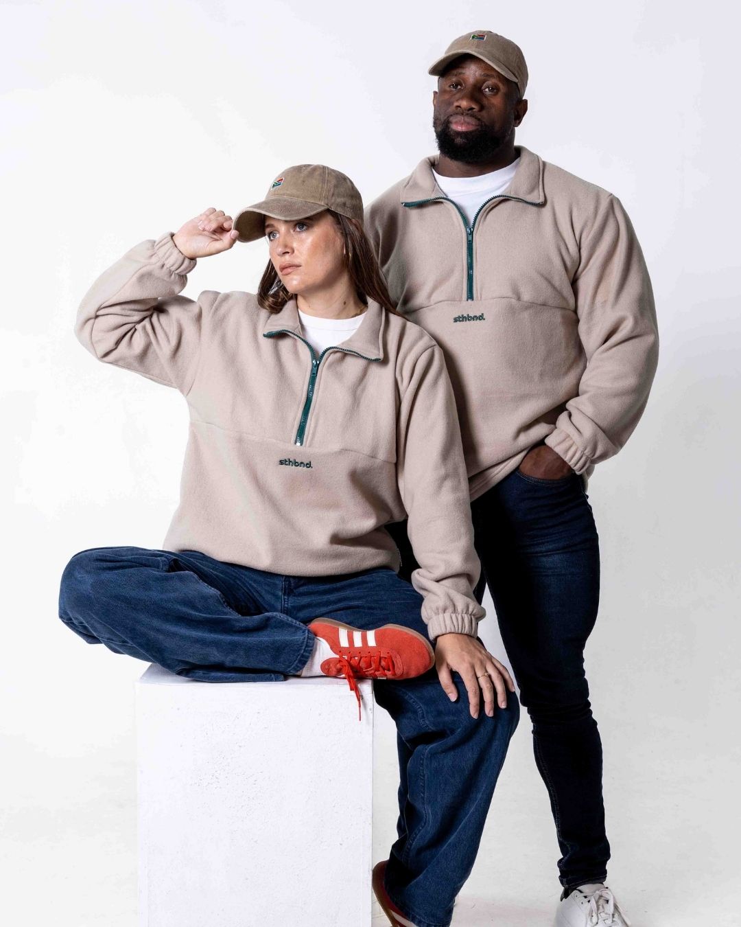 Two people wearing matching beige southbound fleece quarter zips with a visible brand logo on a white background