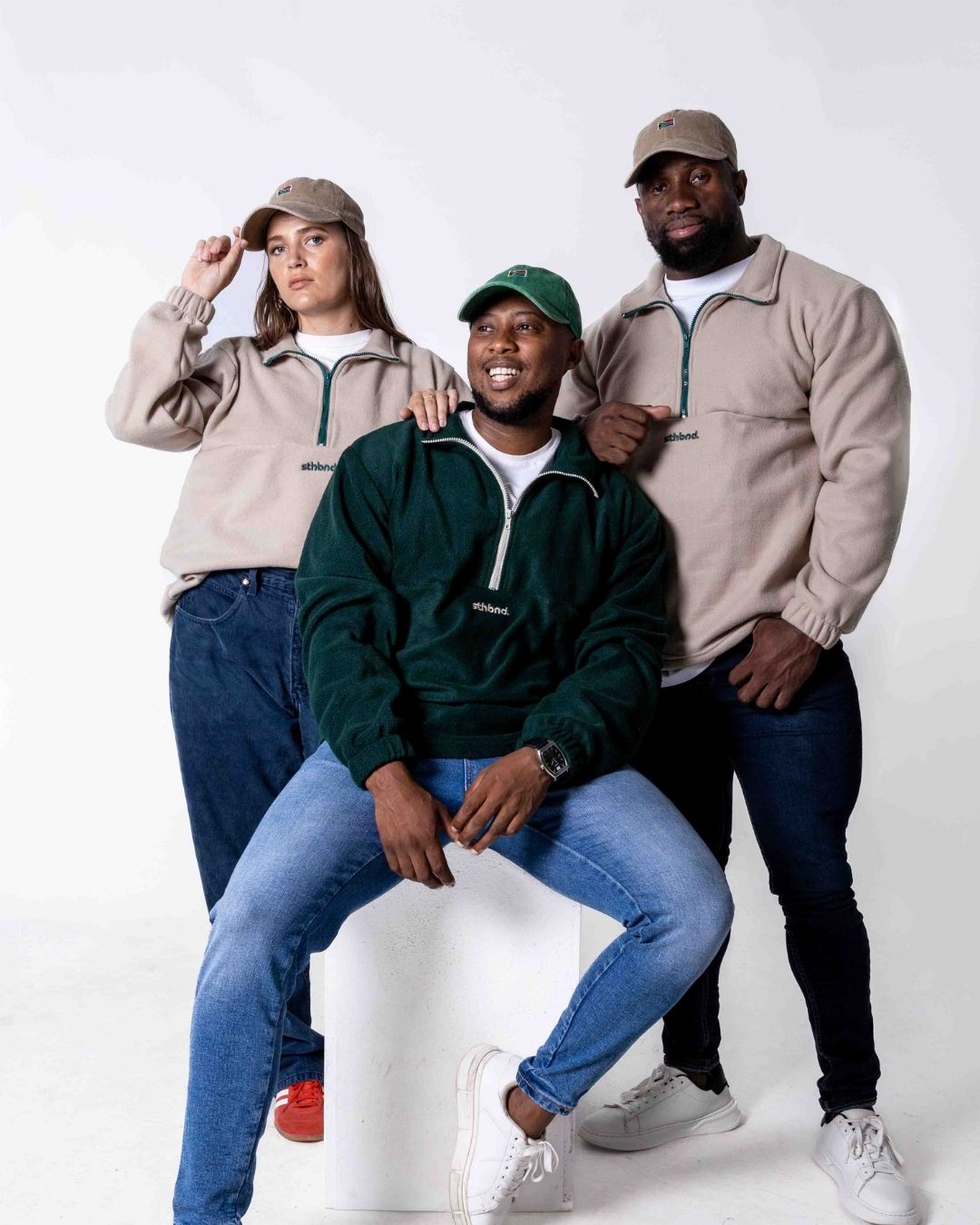 Three people wearing matching outfits with a white background. Green and eige fleece quarter zip jerseys